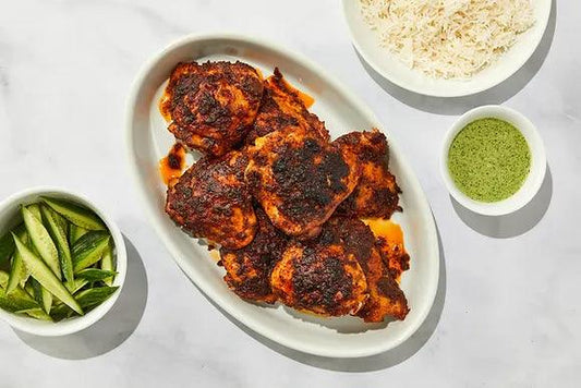 Tandoori chicken moji masala®Homemade tandoori chicken on a white platter with mint chutney, sliced red onion, and lemon wedges — made with moji masala® Tandoori Masala spice blend