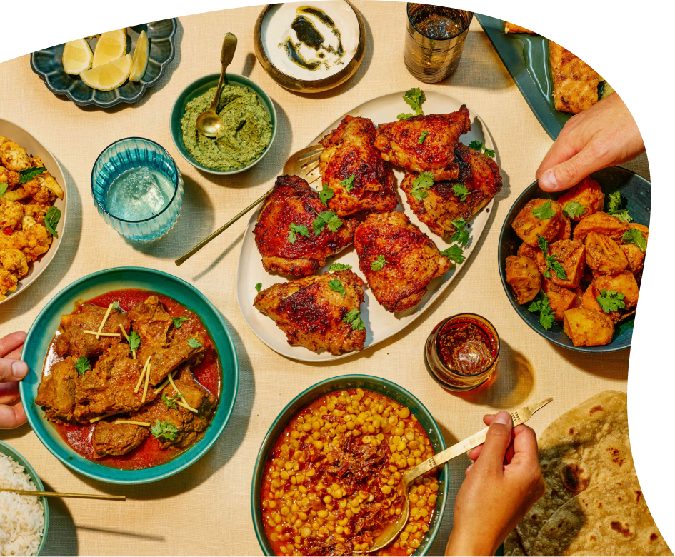 Overhead view of authentic Indian dishes made with moji masala spice blends — chicken curry, rogan josh, and sides