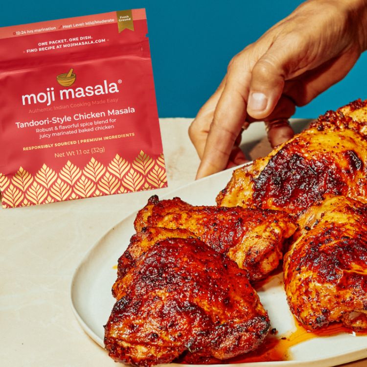 Plated moji masala® Tandoori-style chicken with a 'moji masala' packet on a blue background